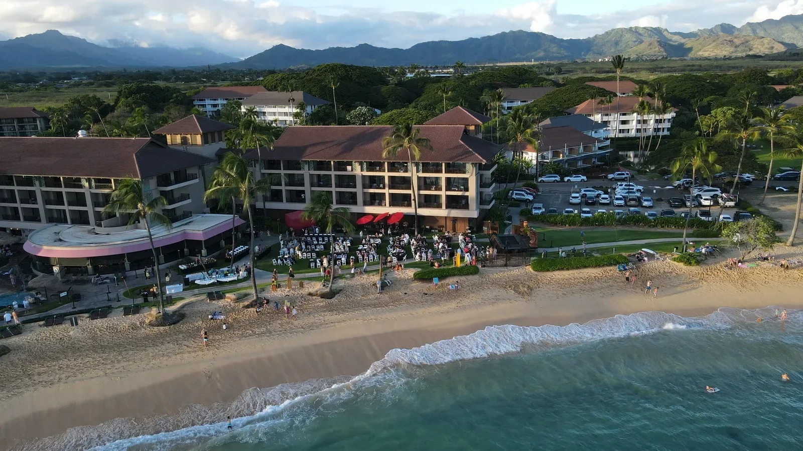 Aerial view of a beachfront resort on Kauaʻi with mountains behind